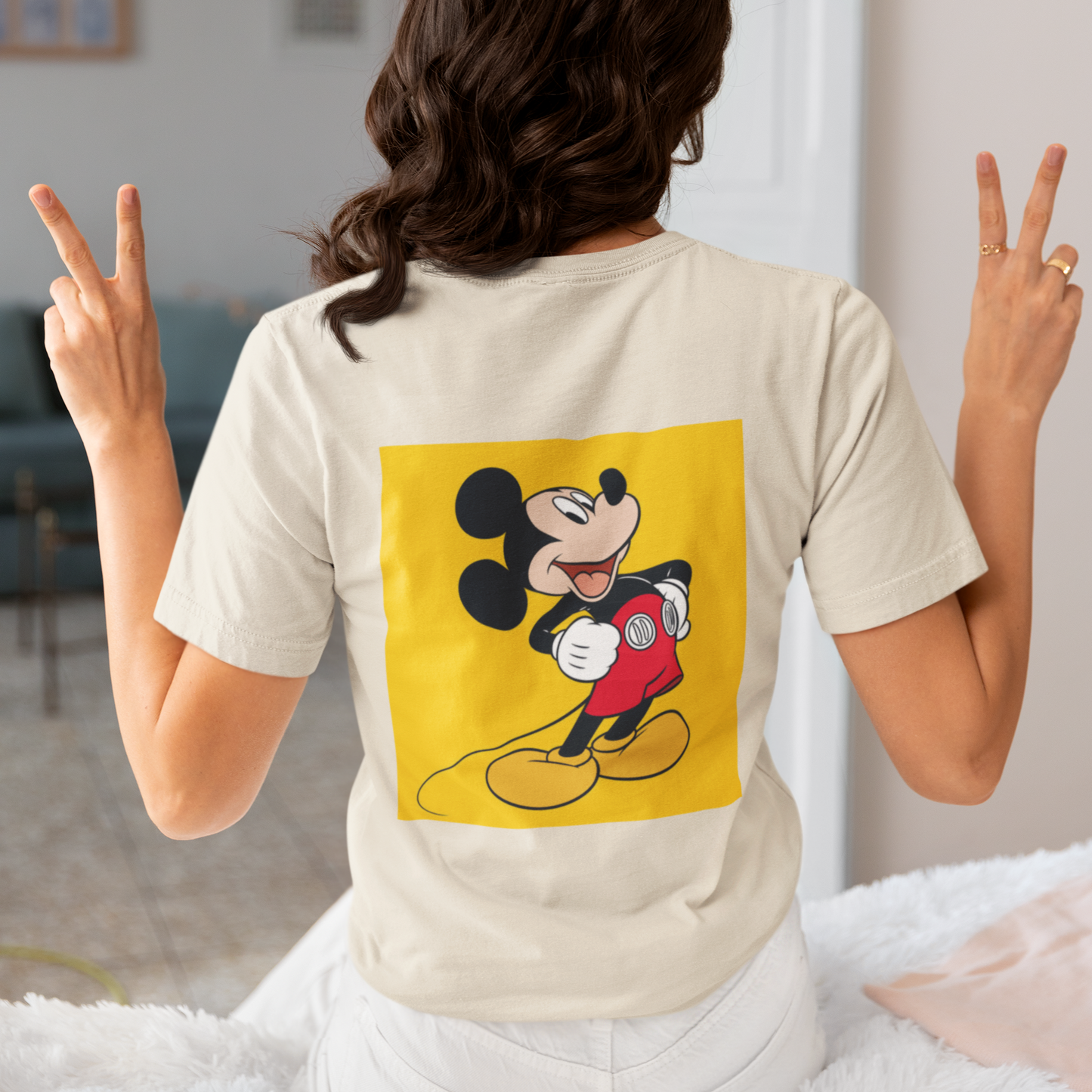 a woman wearing a beige Mickey mouse T-shirt