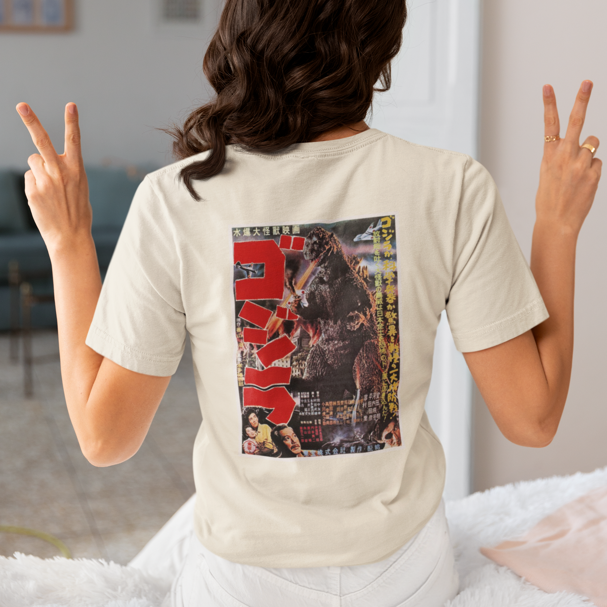 a woman wearing a beige japanese godzilla  t - shirt